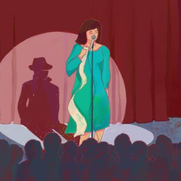 Woman on stage with a microphone and a piece of paper on her hand with her shadow as a stalker wearing a coat and a hat. 