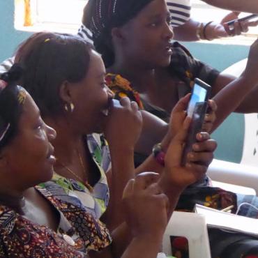 Image description: Three women laughing and looking at mobile phone