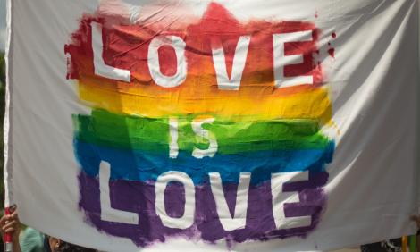 Banner saying Love is Love on rainbow background