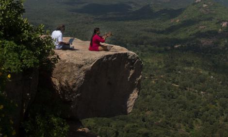 Image description: Two people check equipment on top of hill