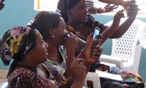 Image description: Three women laughing and looking at mobile phone