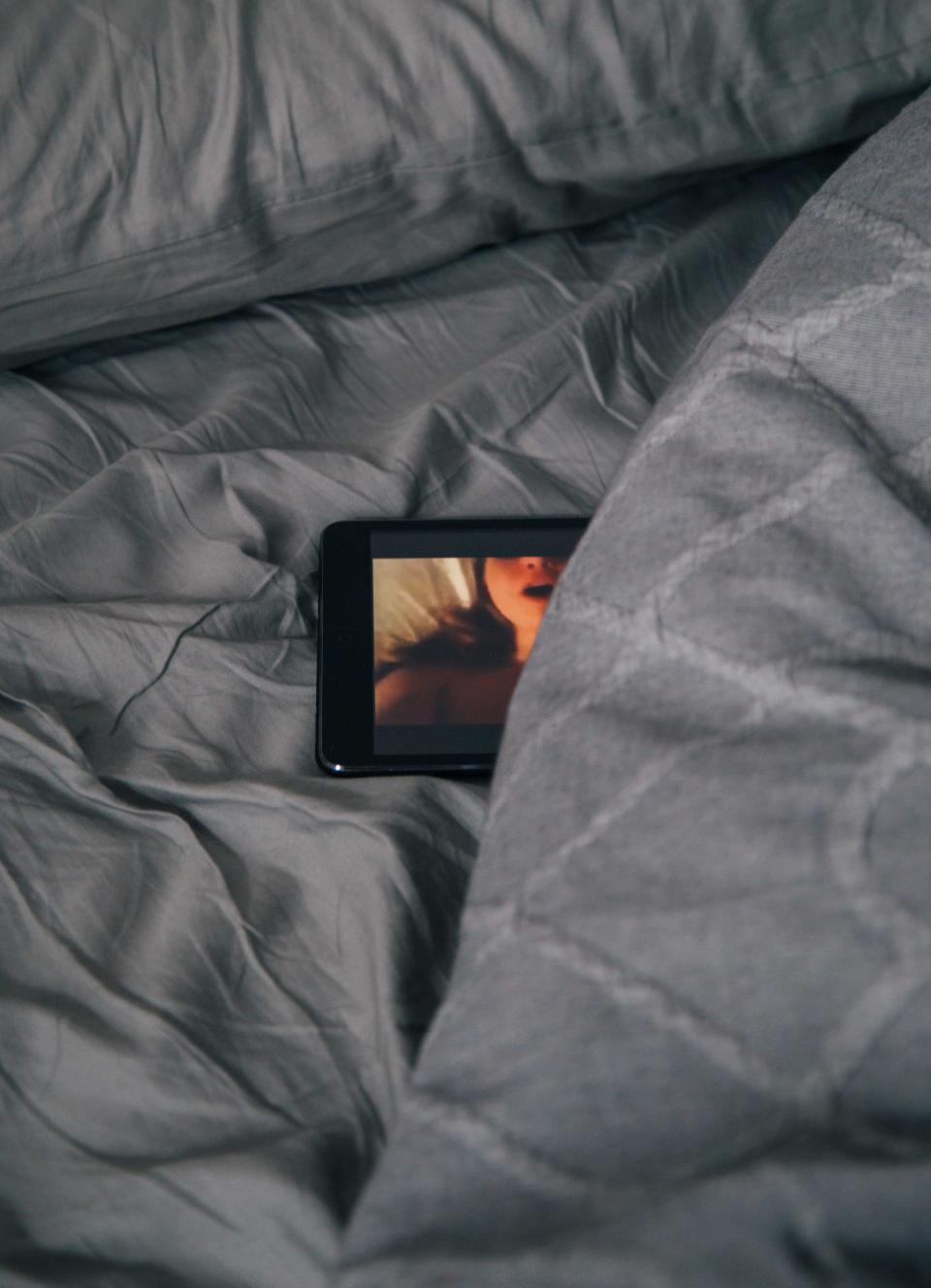 Image description: Tablet lying on bed, image of woman on the screen