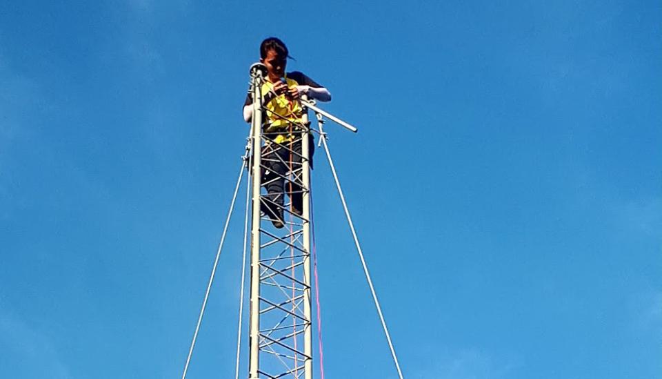 Image description: A person high up on a communications tower