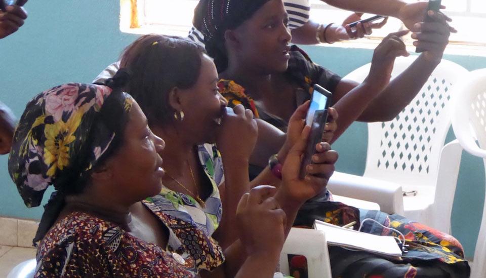 Image description: Three women laughing and looking at mobile phone