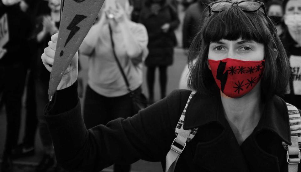 Image description: Woman holding sign